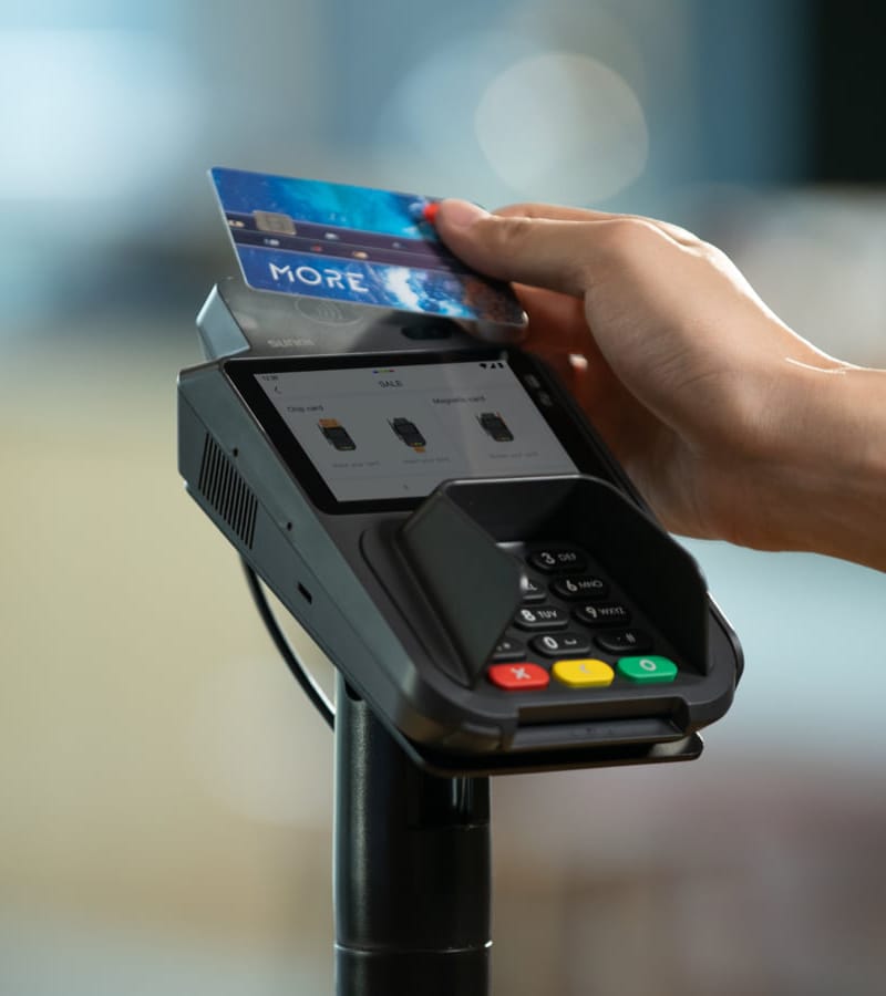 Close-up van een hand die een betaalkaart tegen een pinautomaat houdt — beeld dat contactloos betalen of kassatransacties visualiseert, passend bij thema’s als betalingsverwerking of betaalintegraties (zoals Mollie of MultiSafepay).