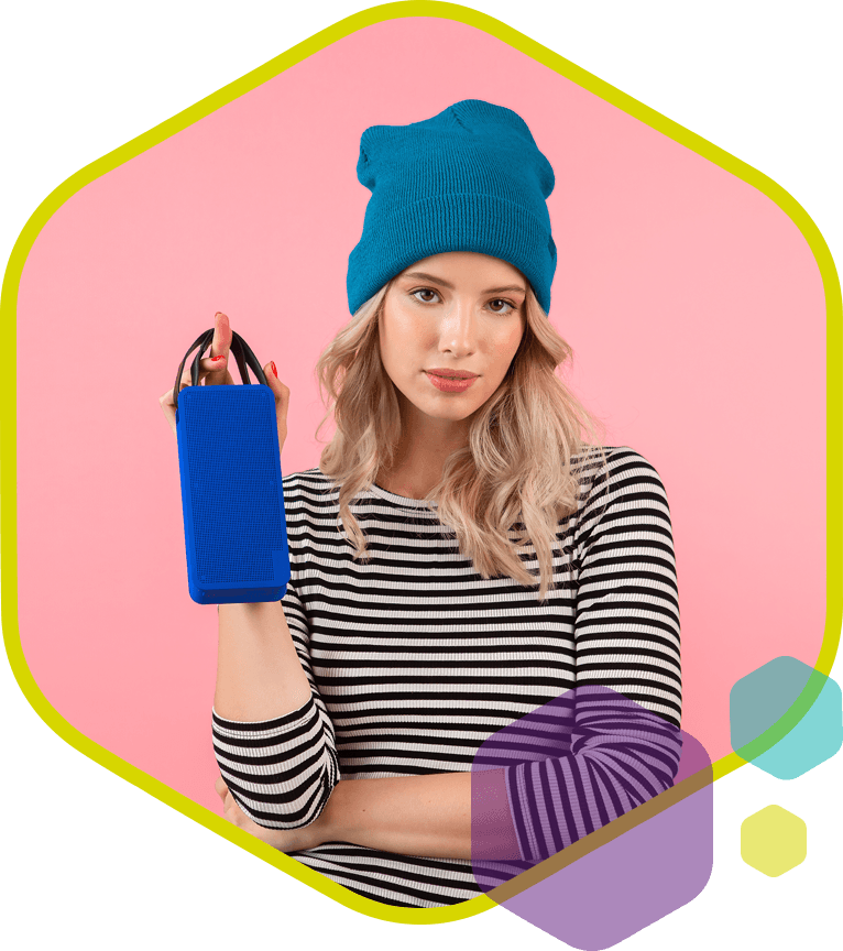 Vrouw met blauwe muts toont draagbare speaker, symbool voor creatieve promotieproducten en moderne merkbeleving