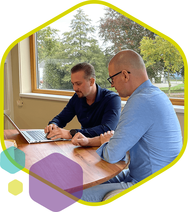 Twee collega’s bespreken innovatieve webshopoplossingen op laptop bij PromoCat